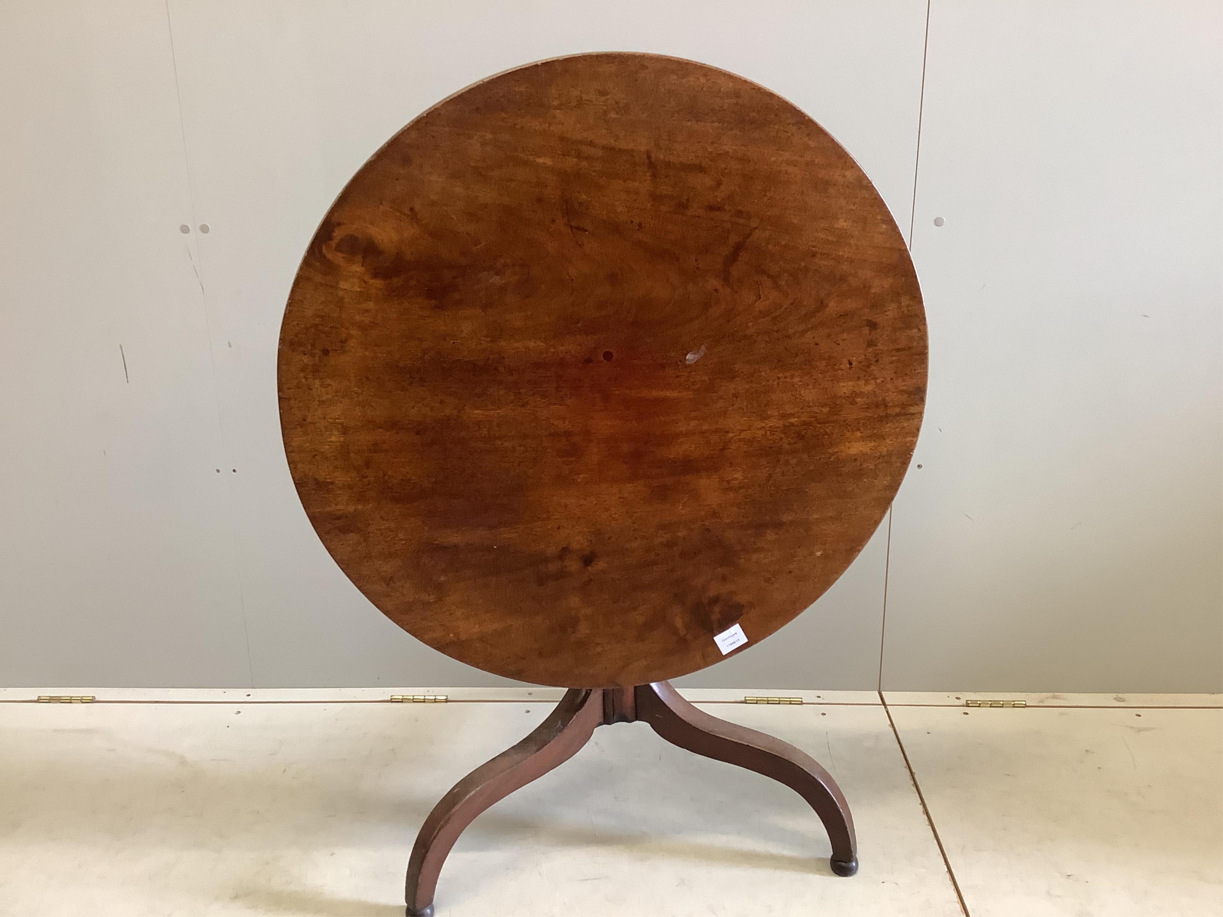 An early 19th century circular mahogany tilt top tripod tea table, diameter 86cm, height 67cm. Condition - fair